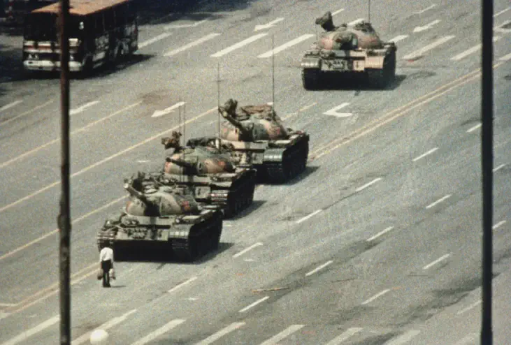 A demonstrator blocks the path of a tank convoy