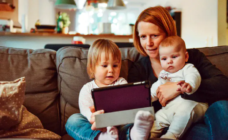 A mother reading an electronic book on a device with her youngsters.