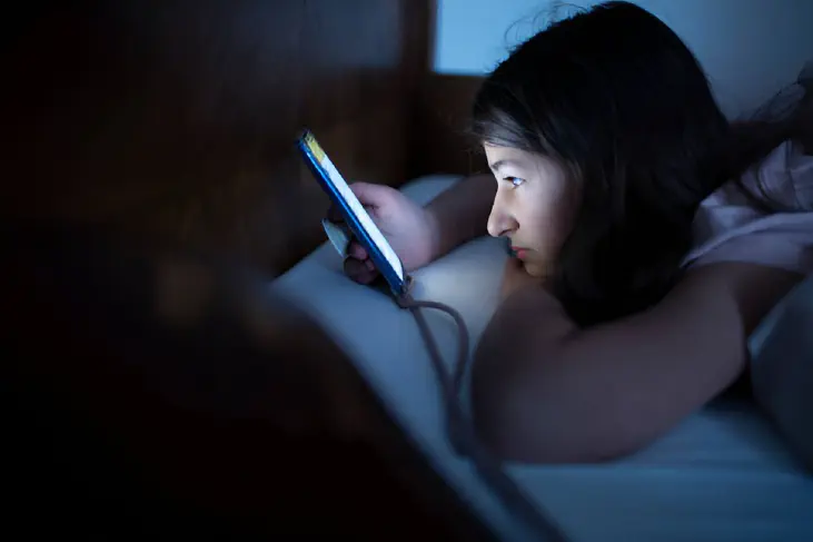 A girl use her gadget in the bed