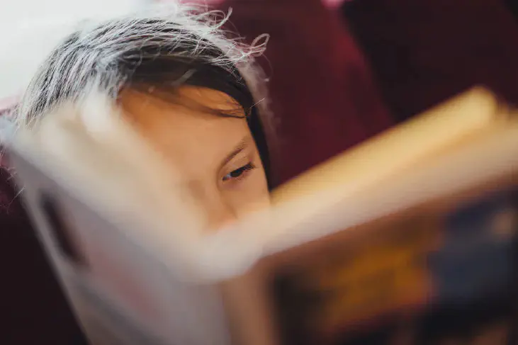 A girl reading a book in front her face