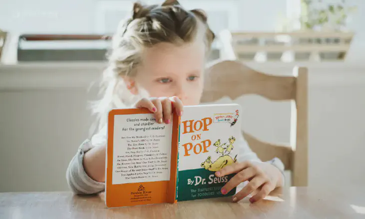 A girl sitting in a chair reading a book