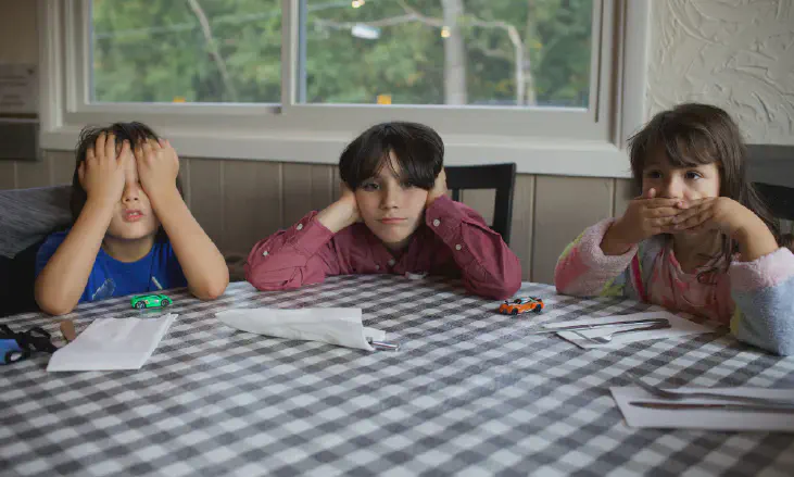 Three children are waiting for the food to be served.